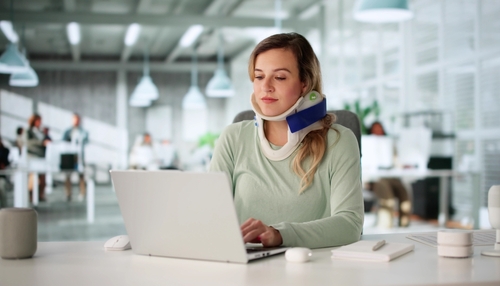 Woman with a neck brace typing on a laptop