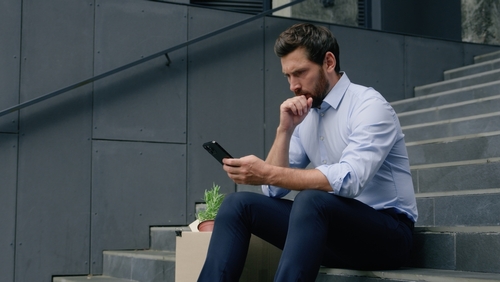 Man sitting on steps looking intently at his phone