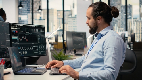 New York Stockbroker Monitoring Trading Charts at Office Desk
