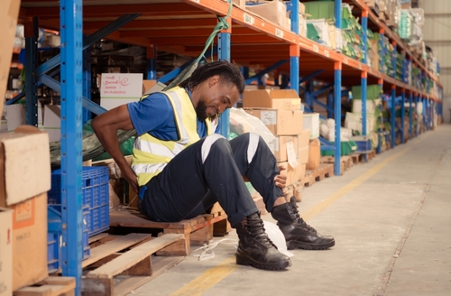 Man holding his back in a warehouse