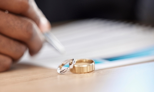 Las Vegas High Asset Divorce Business Division Paperwork Wedding rings beside pen and signed paperwork on desk