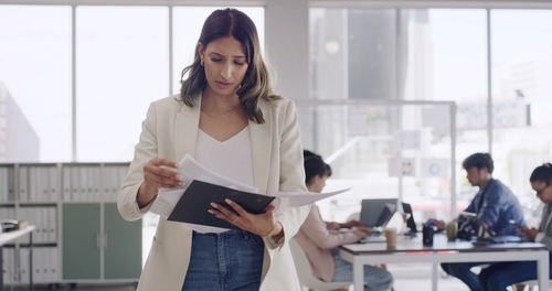 Los Angeles Employee Misclassification 1099 Worker Rights Woman holding documents and touching forehead at office desk with laptop