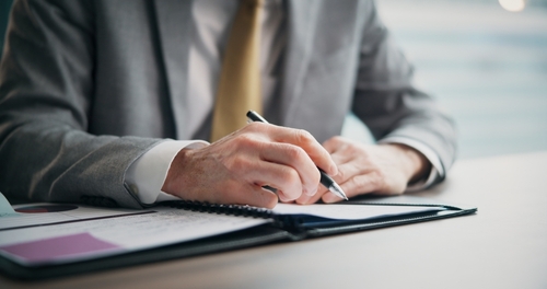 Trust Decanting Documents Gilbert Arizona Attorney Hands writing on documents at desk beside laptop and eyeglasses
