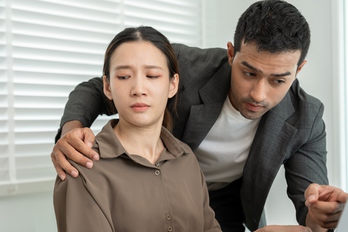 businessman touching female coworker from behind in office setting