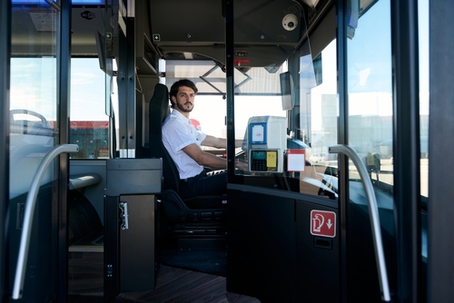 Bus driver seated behind glass partition inside bus driver’s cabin