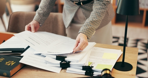 Hands organizing stacked legal documents with binder clips on office desk