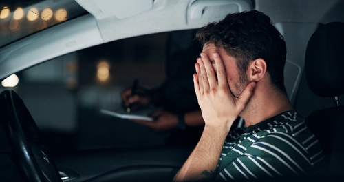 Hombre en parada de tráfico en Phoenix con ansiedad en el auto Conductor sentado en el auto durante una parada de tráfico, mirando ansiosamente hacia el oficial afuera