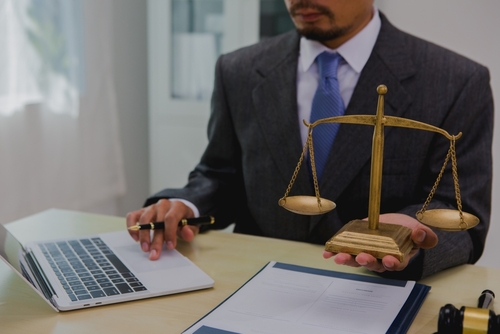 Professional lawyer in suit standing with arms crossed in office setting