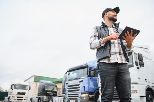 Houston 18-Wheeler Truck Driver Holding Tablet Near Fleet Houston 18-Wheeler Truck Driver Holding Tablet Near Fleet