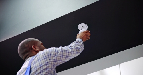 Carbon Monoxide Detector San Antonio Home Safety Worker installing smoke alarm detector on ceiling during fire safety inspection