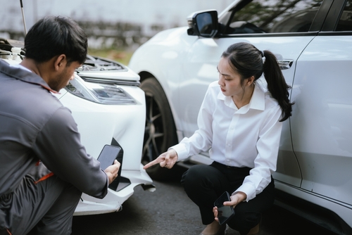 Blue Springs Missouri Car Accident Insurance Claim Consultation Woman points to damaged car bumper while man documents collision beside vehicles