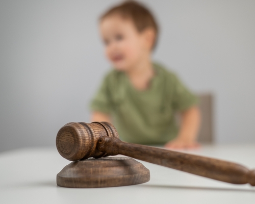 Little boy visible behind judge's gavel on courtroom desk