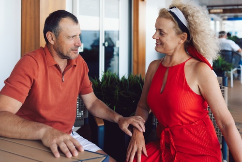 Married couple smiling on cruise ship deck, leaning on railing together