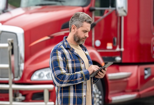 DOT Recordable Accident Inspection Tupelo Mississippi Mechanic using diagnostic tablet beside truck with open hood in service bay
