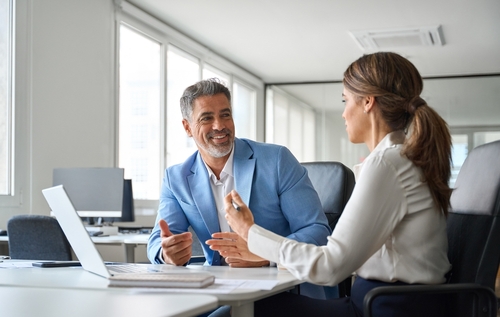 Customer Harassment Lawsuit Redondo Beach California Workplace Two business professionals conversing at conference table beside laptop in office meeting