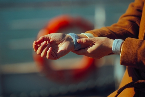 Woman wearing anti-nausea wristband and holding hand to mouth