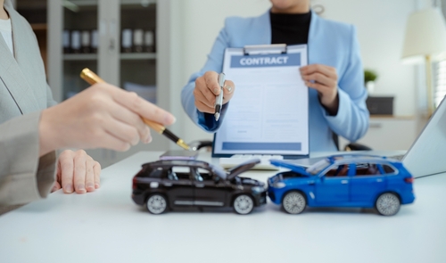 Philadelphia Car Accident Insurance Claim Review Insurance agent reviewing broken car with clipboard beside driver after collision