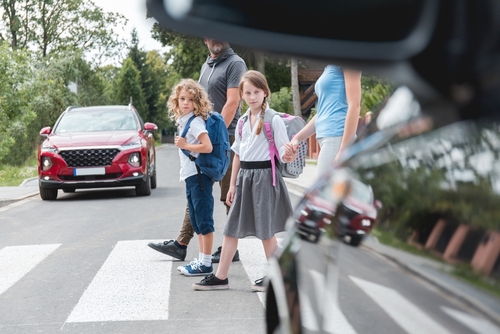 Group of schoolchildren walking through park with backpacks and notebooks