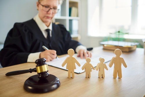 Las Vegas Judge Reviewing Nevada Spousal Support Factors Judge writing at desk with gavel and wooden family figures in foreground