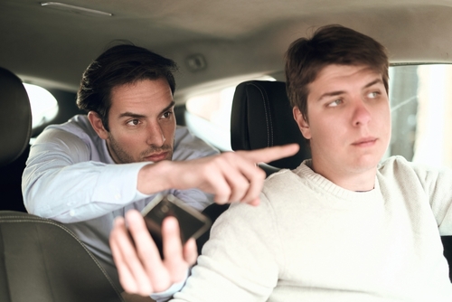 Man seated in taxi backseat while driver navigates city street