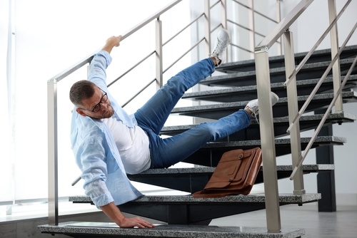 Man Falling on Stairs Slip and Fall Accident Aurora IL Man slipping on building stairs while holding briefcase and reaching for handrail