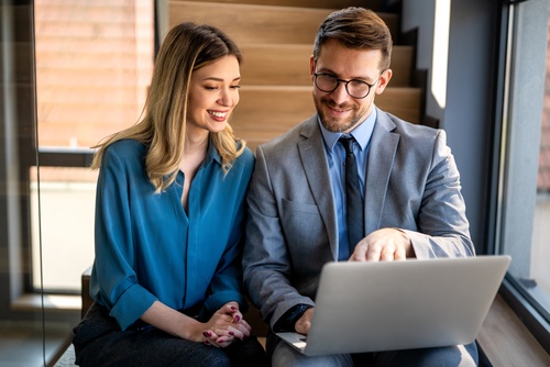 Two business professionals reviewing laptop together in office meeting setting