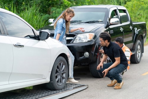 Two people arguing beside damaged cars after roadside collision
