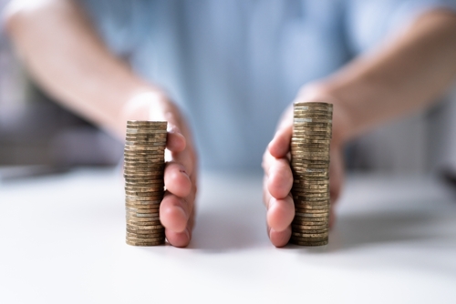 Hands separating two stacks of coins on table, symbolizing divorce asset division