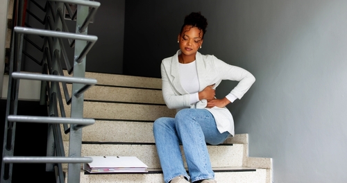 Woman slipping down workplace stairs while holding handrail and briefcase