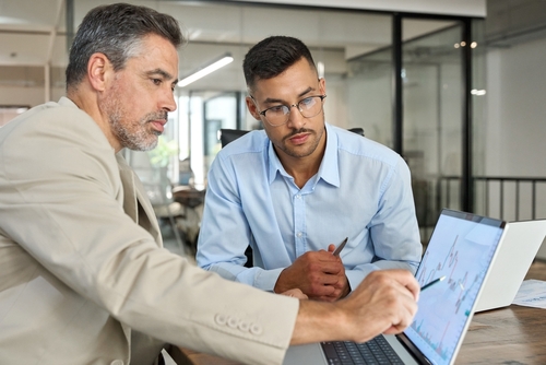 Two business professionals reviewing laptop chart during office meeting