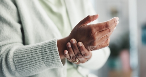 elderly person clutching wrist with both hands indicating wrist pain