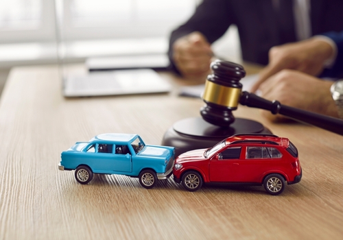 Nebraska I-80 Pileup Multi-Vehicle Crash Legal Claim two toy cars colliding on desk beside judge gavel during legal proceeding