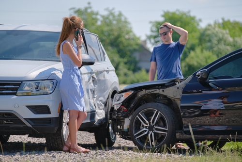 two drivers standing beside smashed vehicles after roadside collision calling for help