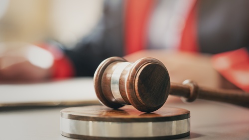 wooden judge gavel resting on sound block on courtroom desk