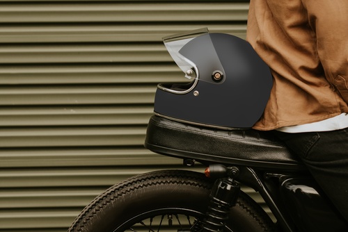 motorcycle helmet resting on leather seat beside standing rider