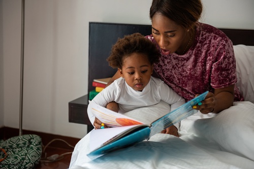 Mother and Child Reading During Joint Physical Custody Las Vegas woman reading illustrated picture book with young child on bed