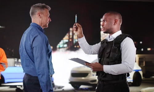 officer in tactical vest administering pen follow DUI field sobriety test at night