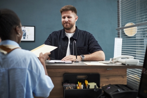 professional at desk receiving document from client during office consultation