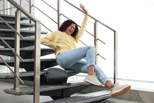 Woman Suffering Back Injury After Workplace Fall San Bernardino woman slipping and falling on indoor building staircase clutching her back in pain