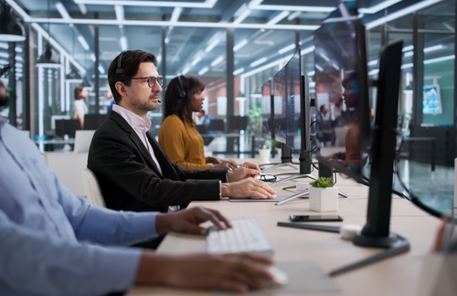 diverse group of professionals wearing headsets working at computer workstations in modern office