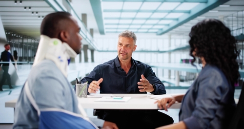 attorney consulting with injured worker wearing neck brace at office table