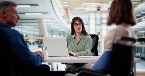 attorney with laptop consulting two clients in modern office setting