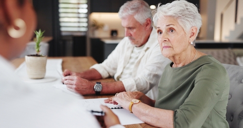 Houston Homeowners Meeting With Denied Insurance Claim Attorney senior couple seated at table reviewing documents with professional advisor