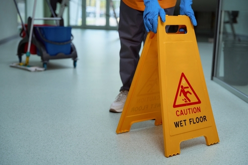 Janitor Placing Wet Floor Caution Sign Westchester Premises Liability janitor placing caution wet floor sign on indoor floor near mop bucket