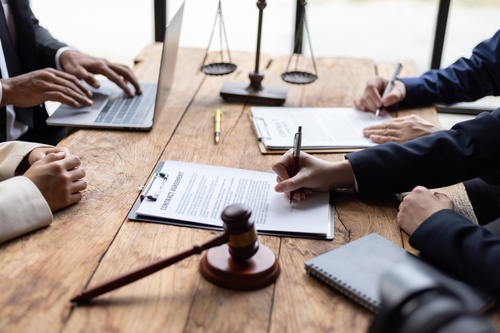 clients signing contract agreement on wooden desk with gavel and scales of justice