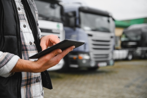 Trucking Company Manager Reviewing Fleet Records Charlotte NC fleet manager holding digital tablet standing in front of commercial trucks