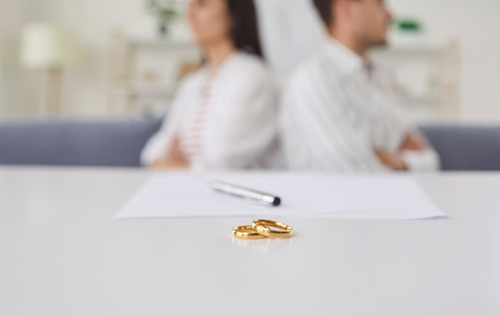 Las Vegas Community Property Divorce Wedding Rings two wedding rings on table beside document and pen couple seated apart
