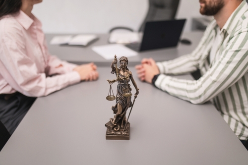 Couple Filing for Divorce With Brooklyn Attorney Kings Highway Lady Justice statue on table between two people during legal meeting