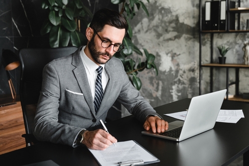 Worcester Bankruptcy Lawyer Reviewing Automatic Stay Garnishment Case suited professional writing on document at desk with open laptop