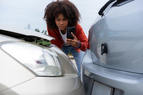Driver Photographing Car Accident Damage in Trenton NJ woman photographing vehicle damage with smartphone after two-car collision